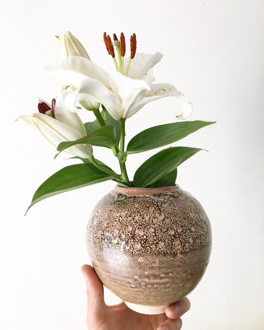 White lilies in a speckled brown-pink round vase